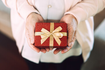 Wall Mural - Close up of christmas red present box holding by senior people hand.