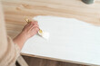 Female hand with a brush to apply white paint on wooden furniture.