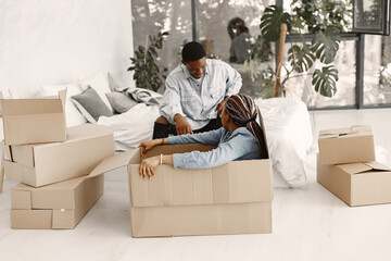 Wall Mural - Young couple moving in to new home together. African american couple with cardboard boxes.