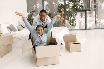 Wall Mural - Young couple moving in to new home together. African american couple with cardboard boxes.