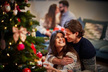 Wall Mural - Adult couples having fun over Christmas tree