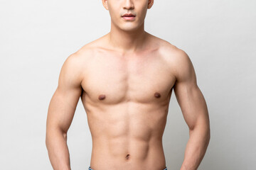 healhty muscular upper body of a shirtless man isolated on light gray studio background