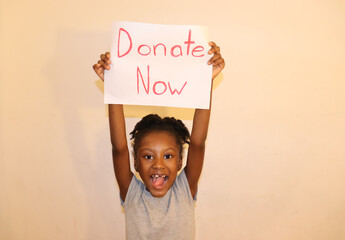 Happy Child Holding a Donate Now Sign up over head white background indoors