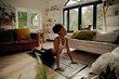 © StratfordProductions - African woman lying on yoga mat at home doing stretching exercise