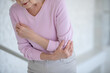 Elderly woman in pink shirt suffering from pain in elbow