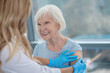 © zinkevych - Long-haired female nurse making vaccination to an elderly woman