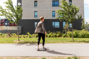 Wall Mural - people and leisure concept - young man or teenage boy riding skateboard on city street