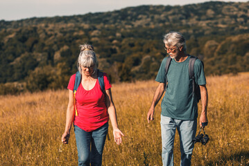 Wall Mural - Active senior couple hiking in nature with backpacks, enjoying their adventure in nature.