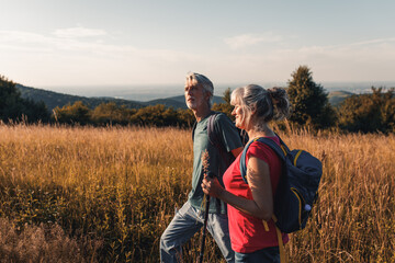 Wall Mural - Active senior couple hiking in nature with backpacks, enjoying their adventure in nature.