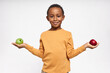 Portrait of confident black boy with cheerful smile posing isolated with green and red apples in his hands, going to have healthy snack instead of fast food. Health, nutrition, dieting and vitamins