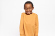 © Anatoliy Karlyuk - Adorable Afro American kid in yellow sweater looking down shyly having timid facial expression, smiling broadly posing against studio background with copy space for your advertising content