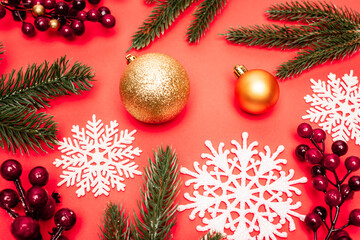 Canvas Print - top view of spruce, baubles, snowflakes and berries on red background