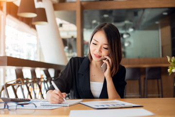 Portrait of Young asian businesswoman beautiful charming smiling and talking on the mobile phone in the office.Business people employee freelance online marketing e-commerce, work from home concept 