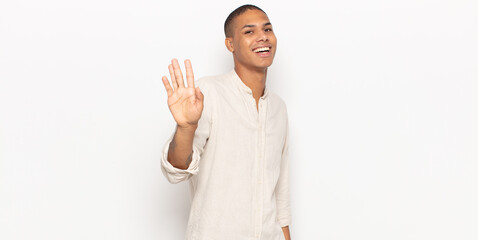 Wall Mural - young black man smiling happily and cheerfully, waving hand, welcoming and greeting you, or saying goodbye