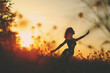 Silhouette of a slender poetic girl in a field at sunset among the tsevts