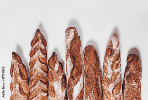 Various types of Bakery bread - fresh rustic crusty loaves of bread and baguette on white background.  (top view, flat lay).