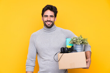 Wall Mural - Young handsome man with beard making a move while picking up a box full of things over isolated background with happy expression