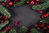 Fototapeta Nowy Jork - Top view of red artificial berries and pine branches on black background, new year concept