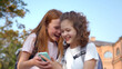 © TommyStockProject - Portrait of cheerful preteen girls using smartphone standing outdoors