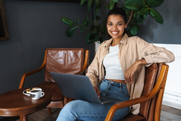 Wall Mural - Smiling african american woman working with laptop