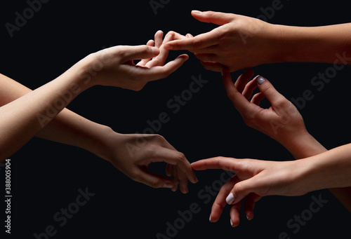 Loving. Hands of people\'s crows in touch isolated on black studio background. Concept of human relation, community, togetherness, symbolism. Light and weightless touching, creating one unit.