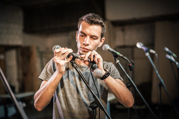 Wall Mural - Theater audio technician adjusting an microphones on the scene. Installing and testing the sound system in the background