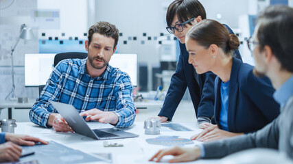 Fototapete - Factory Meeting Room: Multi-Ethnic and Diverse Team of Engineers, Managers, Investors Talking Sitting at Conference Table, Analyzing Blueprints, Mechanism Component. High-Tech Manufactory Optimization