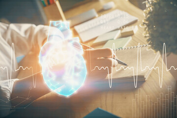 Heart hologram over woman's hands writing background. Concept of Medical study. Multi exposure