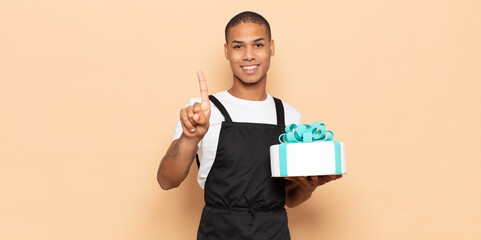 Sticker - young black man smiling and looking friendly, showing number one or first with hand forward, counting down