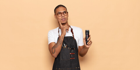 Wall Mural - young black man smiling happily and daydreaming or doubting, looking to the side