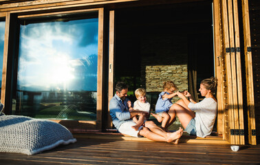 Wall Mural - family with small children sitting on patio of wooden cabin, holiday in nature concept.