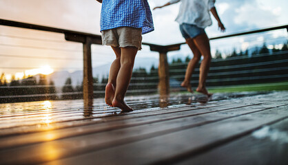 Wall Mural - unrecognizable mother with small daughter playing on patio of wooden cabin, holiday in nature concep