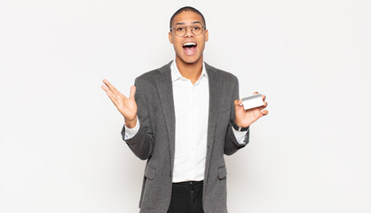 Wall Mural - young black man feeling happy, excited, surprised or shocked, smiling and astonished at something unbelievable