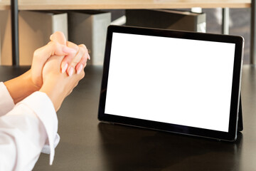 Online conference. Corporate teamwork. Distance work. Unrecognizable woman white shirt clasping hands looking at tablet computer blank screen wooden table office workplace copy space.