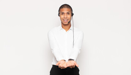 Sticker - young black man smiling happily with friendly, confident, positive look, offering and showing an object or concept