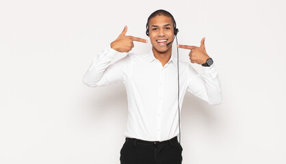 Wall Mural - young black man smiling confidently pointing to own broad smile, positive, relaxed, satisfied attitude