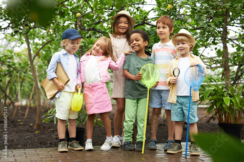 Fotomural happy multi-ethnic group of children have fun, walk in garden or greenhouse, get
