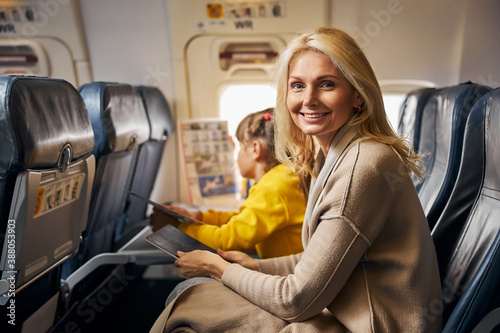 Smiling woman on a plane with a tablet