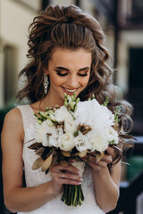 A bride in a white dress is holding a beautiful wedding bouquet.