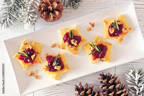 Christmas star shaped appetizers with cranberries and baked brie. Top view table scene against a white wood background.