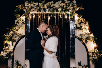 Wall Mural - Newlyweds on the background of the wedding arch. Night fireworks.