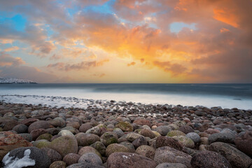 Wall Mural - long exposure of the surf breaking on an arctic boulder beach on the barents sea, above the polar ci