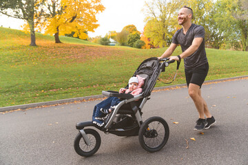 Wall Mural - man with her daughter in jogging stroller outside in autumn nature
