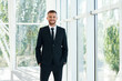 © GVS - Confident smiling businessman in elegant suite posing in modern creative office
