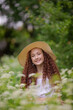 © MARIYA - Cute red girl in straw hat on a flowering clearing at a picnic with fruit