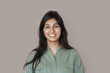 Smiling cheerful young adult indian woman looking at camera, happy pretty funny lady model laughing, feeling positive emotion standing isolated on brown background, face front headshot portrait.