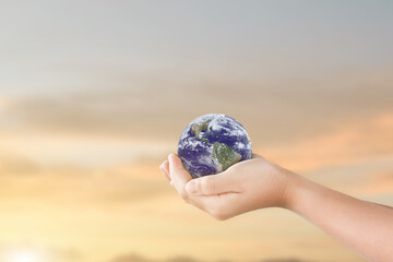 Canvas Print - concept of world environment day: hand holding earth globe over blurred nature sky background. eleme