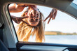 © JOSEP SURIA/Westend61 - Carefree woman showing peace sign while looking through window of car
