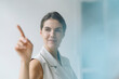 © KNSY/Westend61 - Smiling woman pointing on glass wall while standing at office