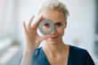 © KNSY/Westend61 - Close-up of smiling businesswoman looking through object in office